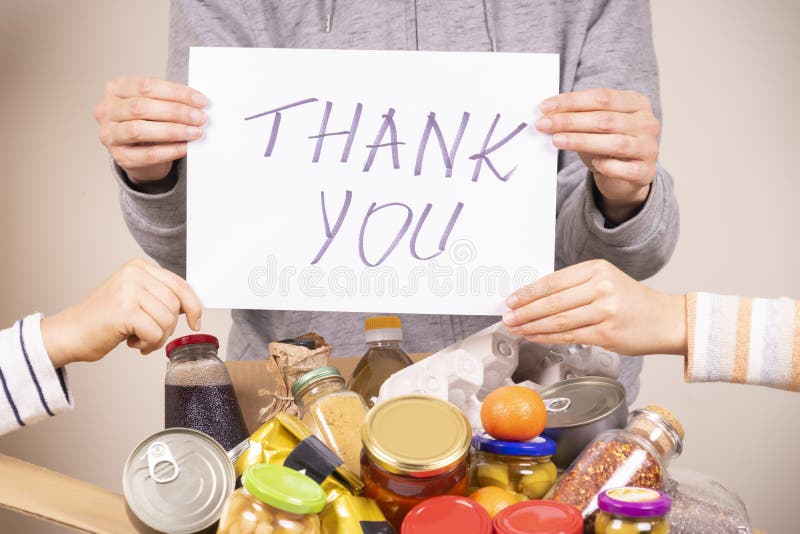 Thank you for donation. Volunteers holding paper sheet with message Thank you over food donation box full of glocery.