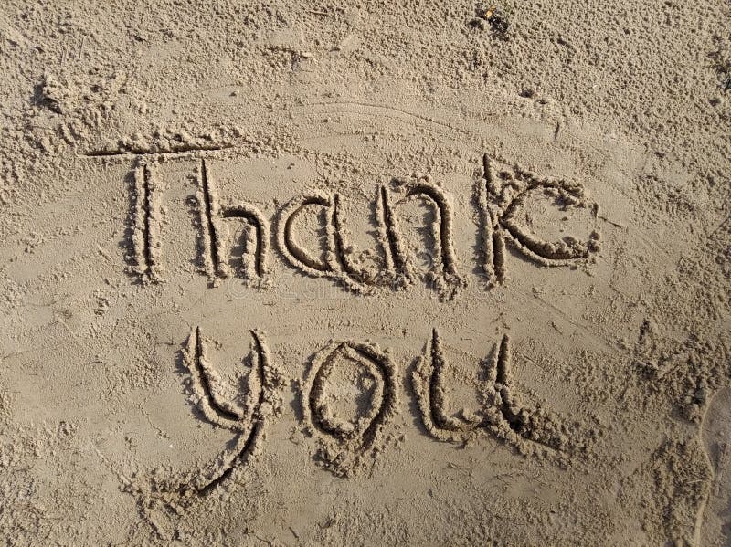 Thank you inscription on wet sand in the sunlight