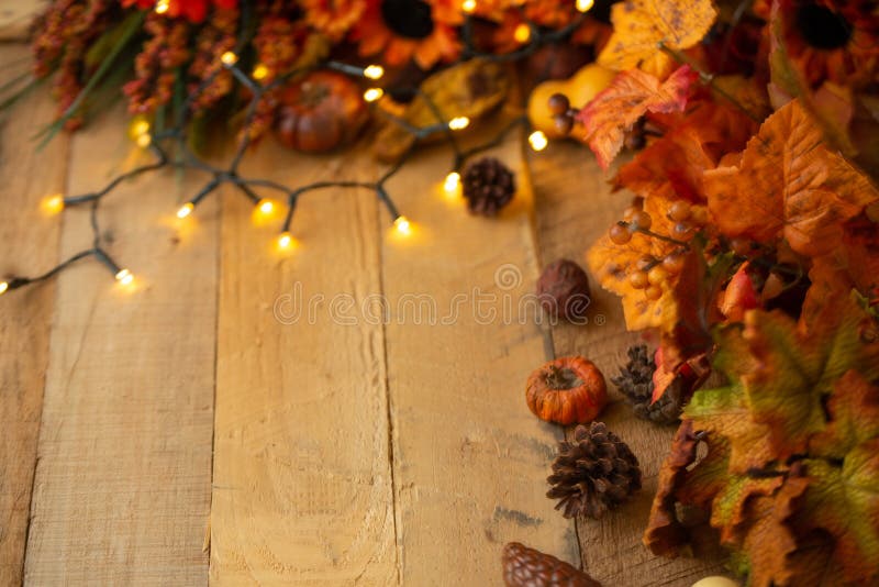 Thanksgiving or Halloween, Autumn composition with dry leaves and small pumpkins on an old wooden table with glowing lights. View