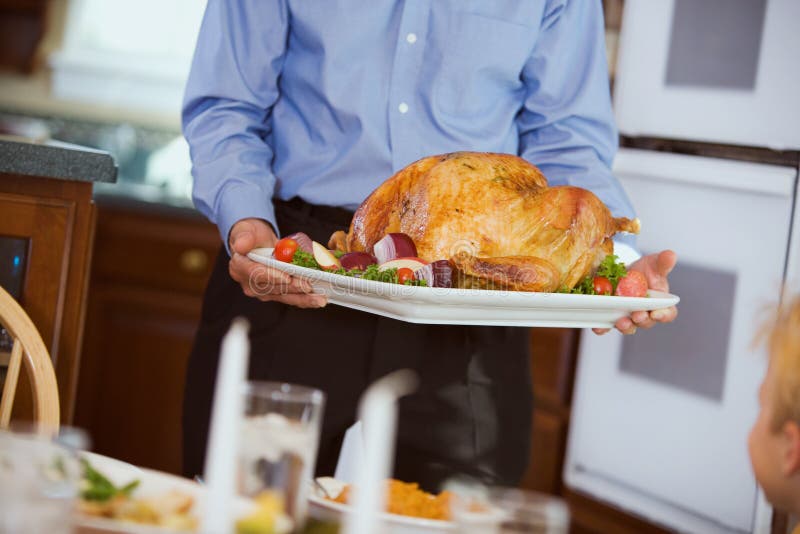 Young and matue men holding tray with homemade roasted turkey over