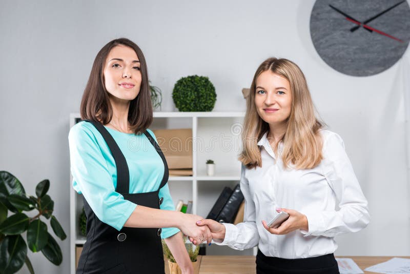 Theme business women. Two young Caucasian women business partners in formal clothes sign a contract, making a deal a handshake in stock image Theme business women. Two young Caucasian women business partners in formal clothes sign a contract, making a deal a handshake in stock image