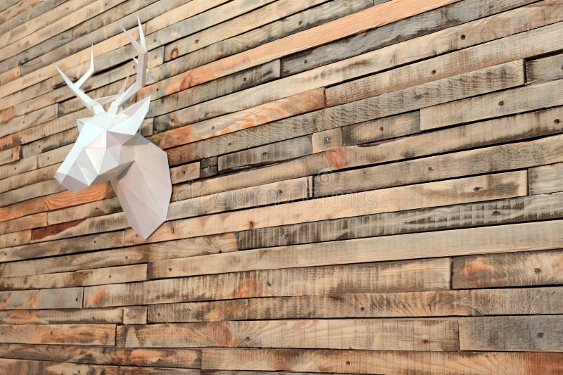 Theme happy new year. Paper deer head hanging on the wall of wooden planks. Perspective at an angle. Copy space.