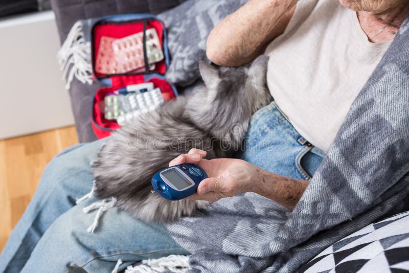 Theme old man and diabetes. Close-up of a hand. Senior Caucasian woman at home on the couch measures level of glucose in stock photography Theme old man and diabetes. Close-up of a hand. Senior Caucasian woman at home on the couch measures level of glucose in stock photography