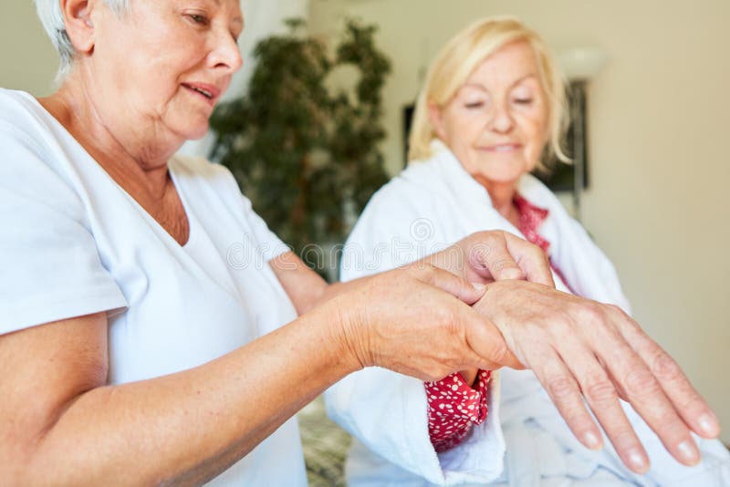 A therapist or nurse does acupressure as pain therapy on the hand of a senior citizen. A therapist or nurse does acupressure as pain therapy on the hand of a senior citizen