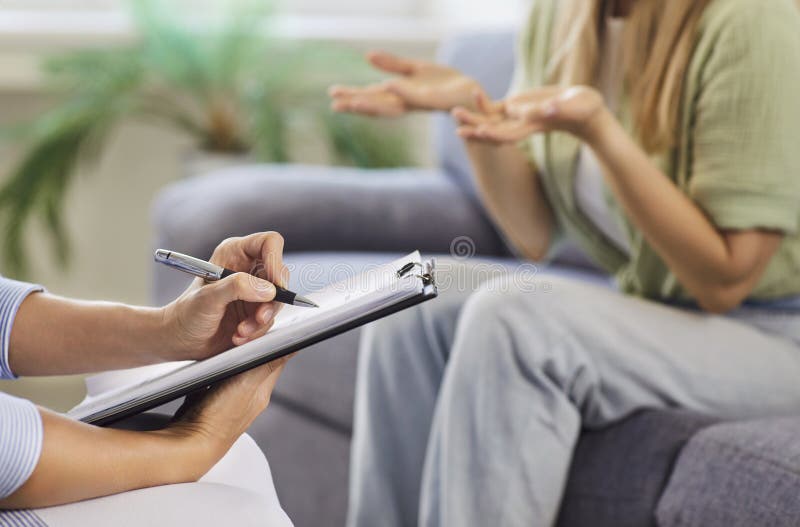 Therapist taking notes while patient gestures during supportive counseling session