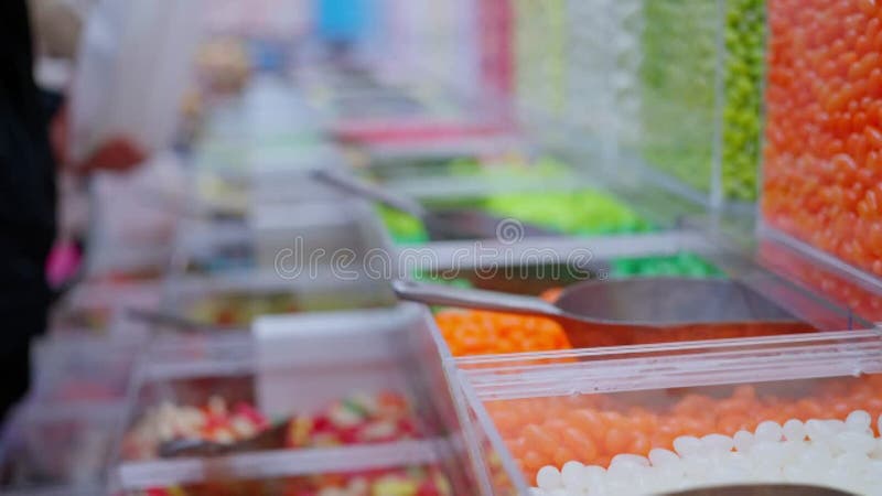 A lot of people in the store of sweets, lollipops, People pick up candies stock video footage