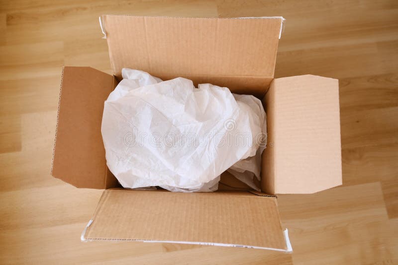 There is an Open Cardboard Box on the Floor, Something is Wrapped in Wrapping Paper Inside, the