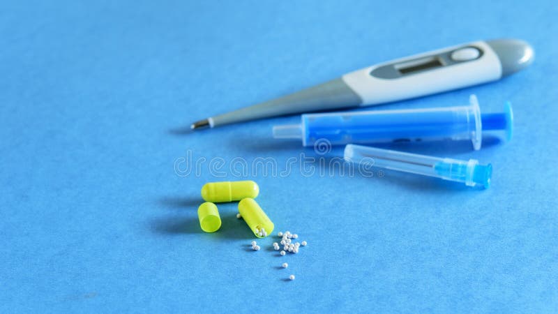 Disposable syringe, thermometer and capsule pills on the blue background. Minimum set against virus or flu. Disposable syringe, thermometer and capsule pills on the blue background. Minimum set against virus or flu