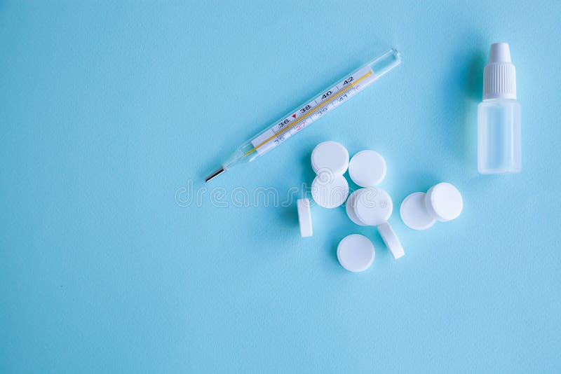 Thermometer, pills and nose drops on a blue background royalty free stock photo Thermometer, pills and nose drops on a blue background royalty free stock photo