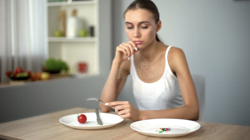 Thin girl looking at anti-obesity pills, obsession with weight loss, addiction stock images Thin girl looking at anti-obesity pills, obsession with weight loss, addiction stock images
