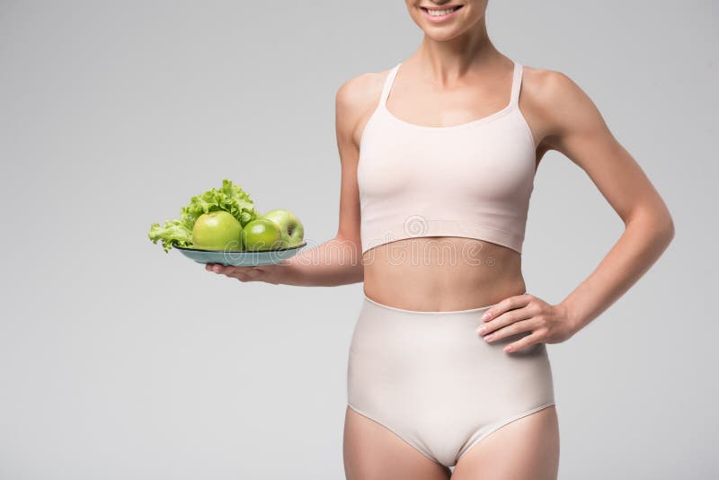 thin-girl-prefers-healthy-eating-cheerful-young-woman-showing-green-apples-lime-lettuce-to-camera-standing-101119016.jpg