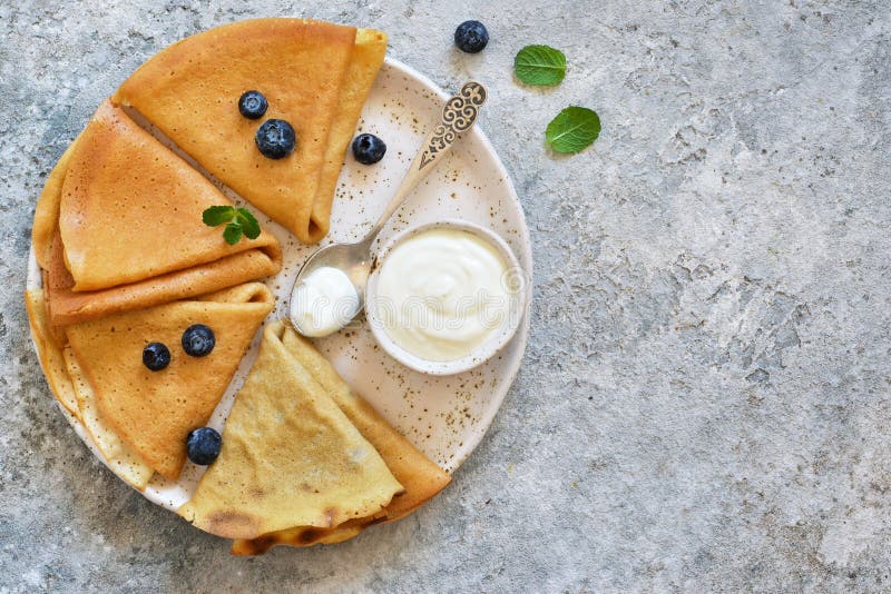 Thin pancakes with vanilla sauce, blueberry and mint on a cement background. stock photos Thin pancakes with vanilla sauce, blueberry and mint on a cement background. stock photos