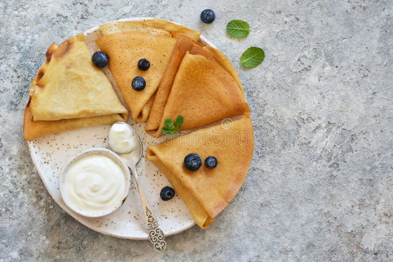 Thin pancakes with vanilla sauce, blueberry and mint on a cement background. View from above royalty free stock photo Thin pancakes with vanilla sauce, blueberry and mint on a cement background. View from above royalty free stock photo