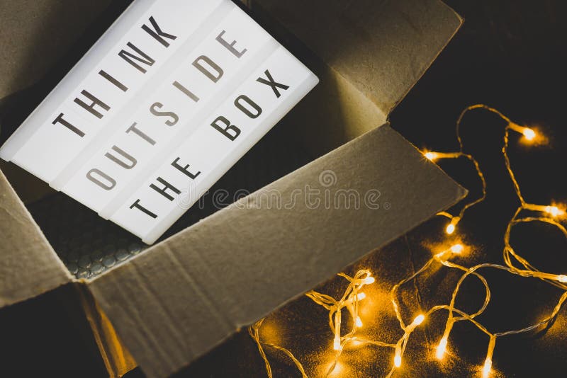 Think outside the box message on lightbox coming out of a parcel with fairy led lights, concept of being unique for success