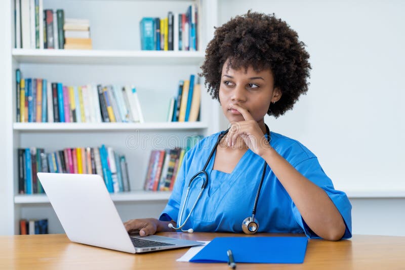 Thinking afro american nurse or medical student at computer royalty free stock photography