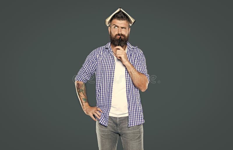 Thinking bearded man with book on head on grey background stock photo