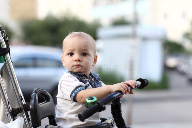 Thinking child on tricycle with push handle on the street