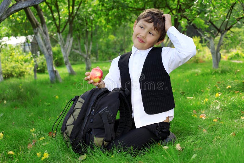 Thinking schoolboy with backpack and apple