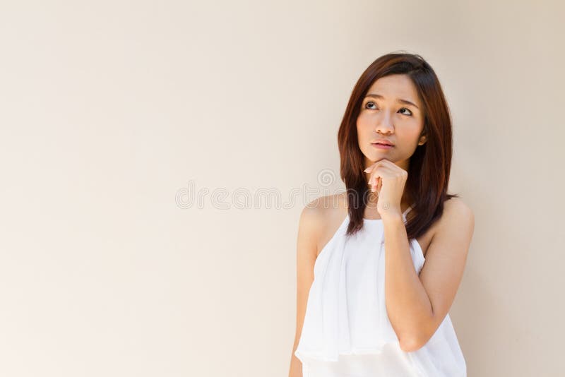 Thinking woman, facing upward on plain warm tone background