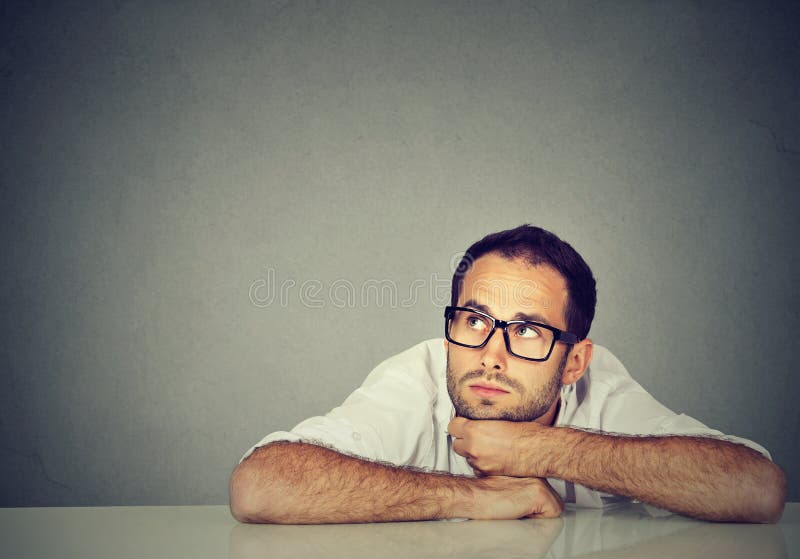 Thinking young business man sitting at table royalty free stock photography