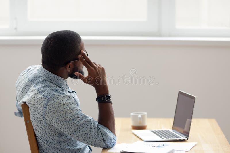 Thoughtful African American businessman looking out window sitting at office