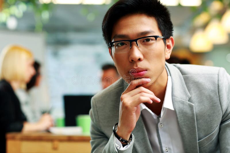 Thoughtful asian man sitting in office