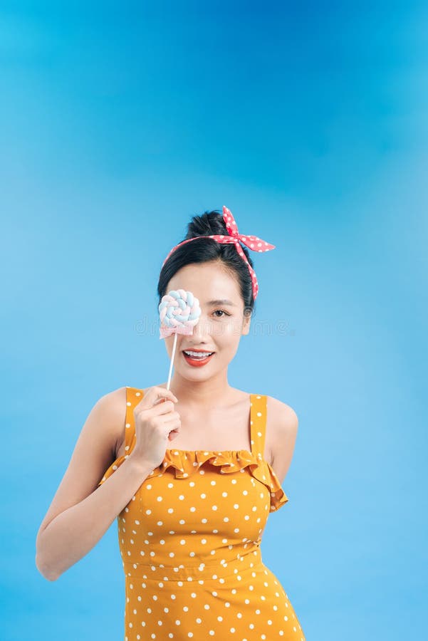 Thoughtful black hair model holding a colored lollipop on blue background