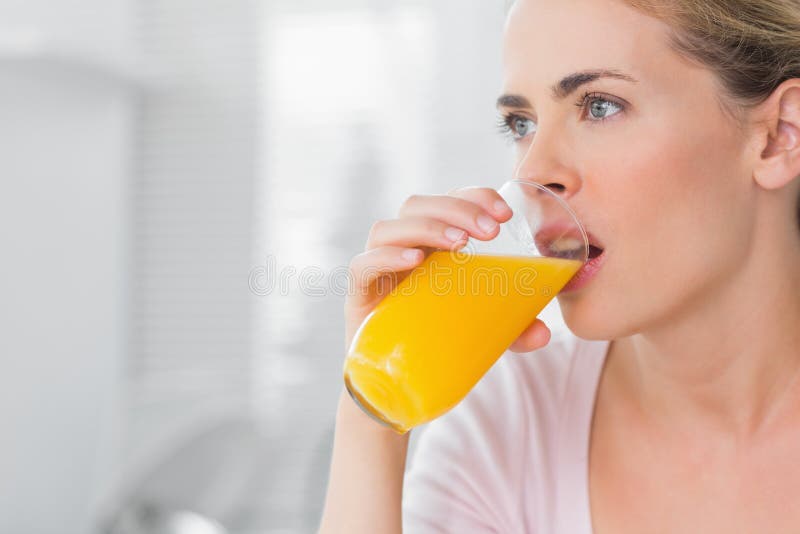 Thoughtful blond woman drinking orange juice royalty free stock photo Thoughtful blond woman drinking orange juice royalty free stock photo
