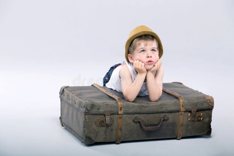 Thoughtful boy lying on the suitcase
