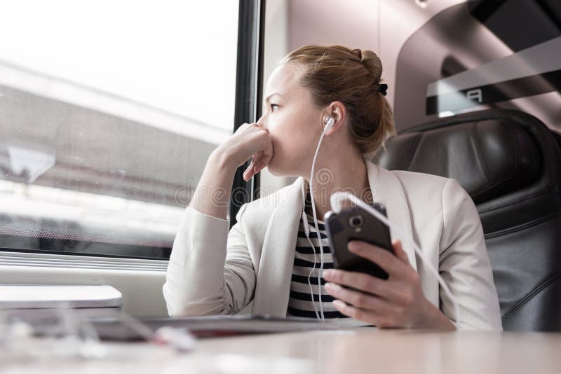 Businesswoman communicating on mobile phone while traveling by train.