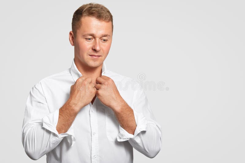 Thoughtful determined businessman in elegant formal white shirt, thinks about something, focused down, has appealing look, stands stock photography Thoughtful determined businessman in elegant formal white shirt, thinks about something, focused down, has appealing look, stands stock photography