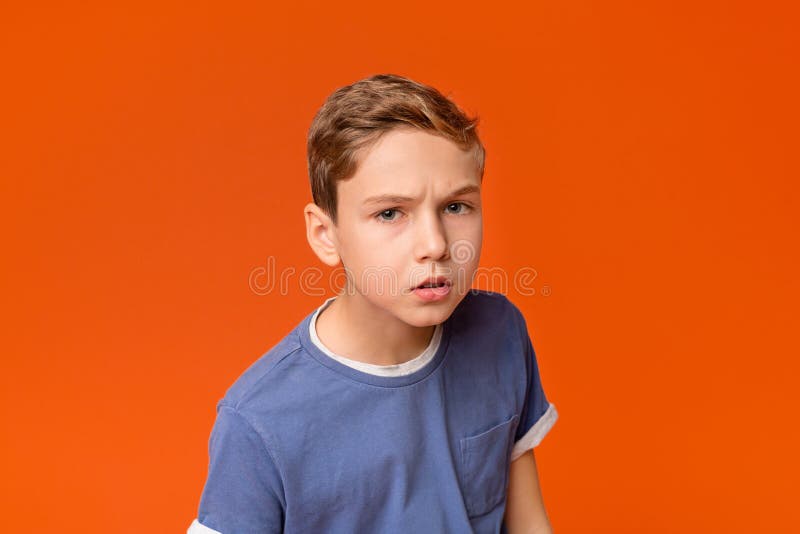 Thoughtful dissatisfied curious teen boy closeup portrait, orange studio background