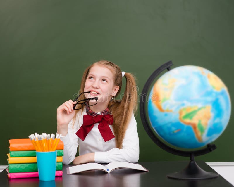 Thoughtful girl looking away near empty chalkboard royalty free stock photo