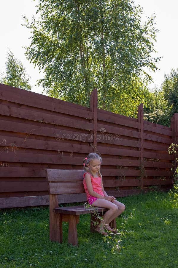 Thoughtful girl sitting on wooden bench royalty free stock photography Thoughtful girl sitting on wooden bench royalty free stock photography