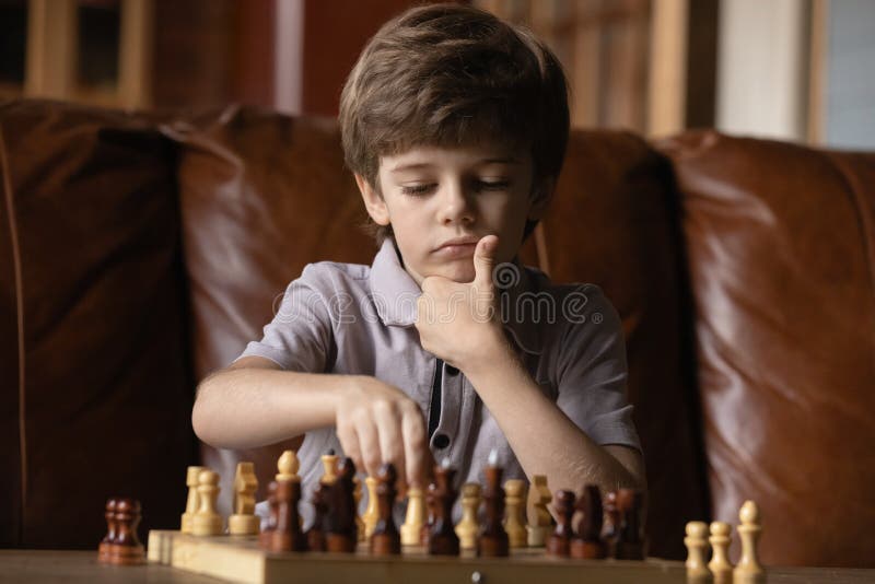 Pupil kid thinking about his next move in a game of chess. Concentrated  little boy sitting at the table and playing chess Stock Photo - Alamy