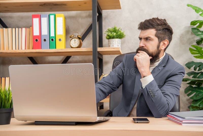 Thoughtful man using laptop working at office desk, decision-maker royalty free stock photo