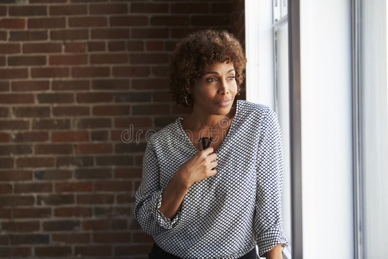 Thoughtful Mature Businesswoman Looking Out Of Office Window