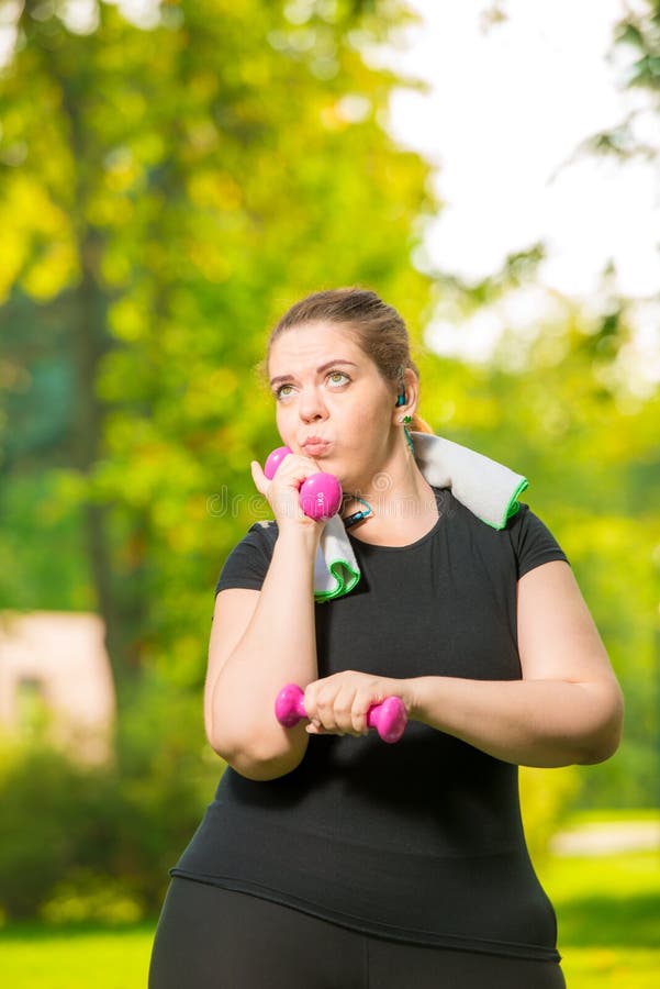 thoughtful plus-size model listens to music with headphones and practices dumbbells during a workout royalty free stock photos thoughtful plus-size model listens to music with headphones and practices dumbbells during a workout royalty free stock photos