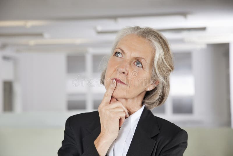 Thoughtful senior businesswoman looking up in office