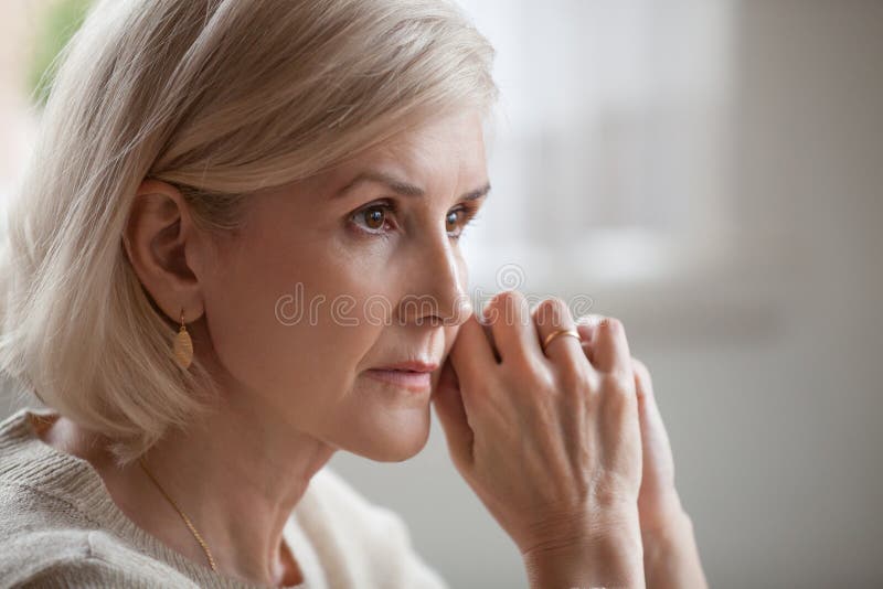 Thoughtful serious anxious mature senior woman feeling blue worried about problems, pensive upset sad middle aged grey haired lady looking away thinking of loneliness, getting older and depression. Thoughtful serious anxious mature senior woman feeling blue worried about problems, pensive upset sad middle aged grey haired lady looking away thinking of loneliness, getting older and depression