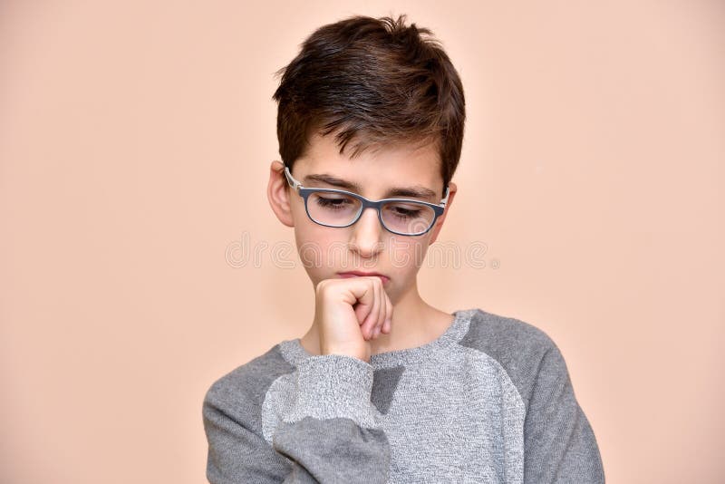 Zamyšlený roztomilý mladý chlapec s brýlemi.