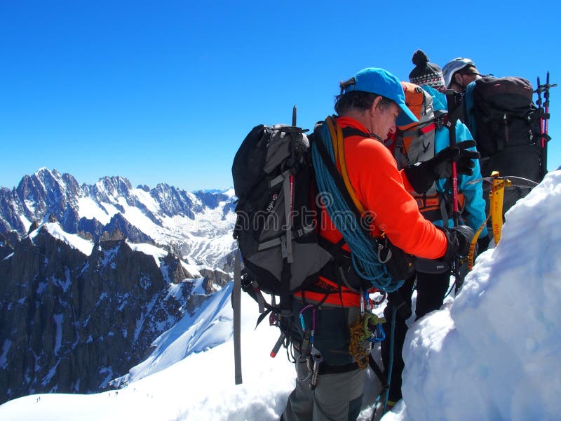 AIGUILLE DU MIDI, FRANCE EUROPE on JULY 2016: Three alpinists, mountaineer climber in french ALPS at CHAMONIX MONT BLANC, top alpine mountains range landscape with clear blue sky in warm sunny summer day.