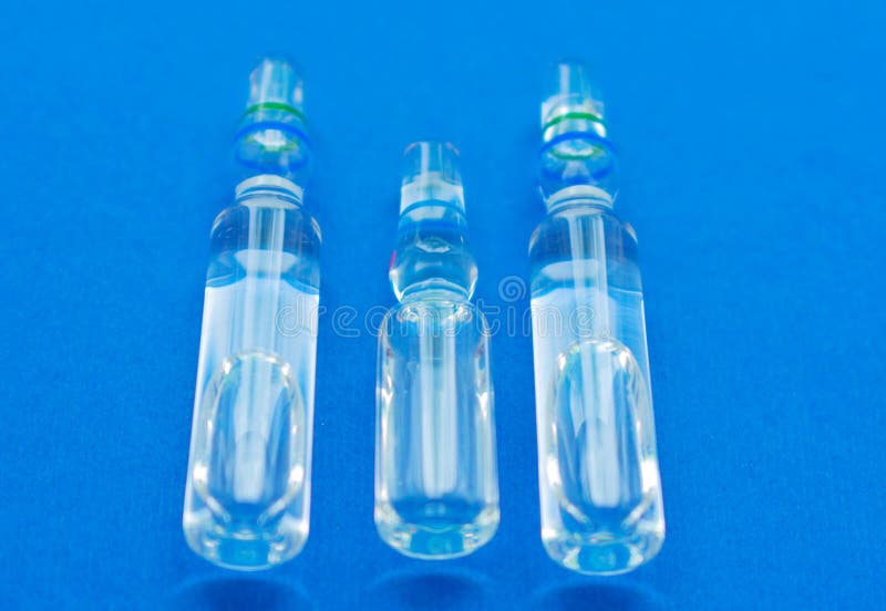 Three Glass Ampoules With Solution For Infectious Closeup On A Blue