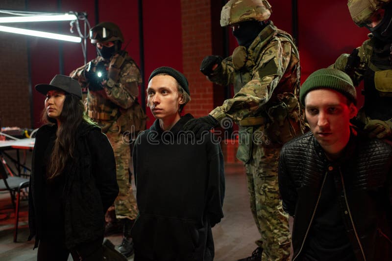 Three arrested cyber criminals and officers in military outfit stock photo