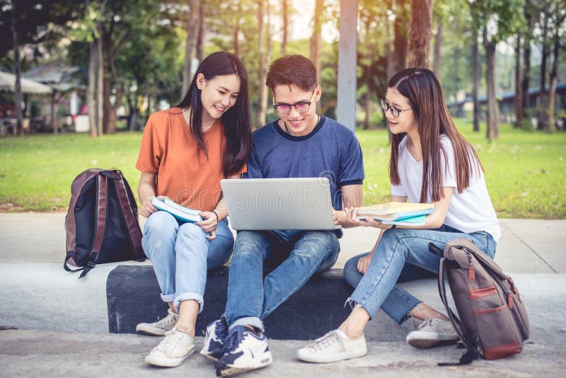 Three Asian young campus students enjoy tutoring and reading books together. Friendship and Education concept. Campus school and stock image Three Asian young campus students enjoy tutoring and reading books together. Friendship and Education concept. Campus school and stock image
