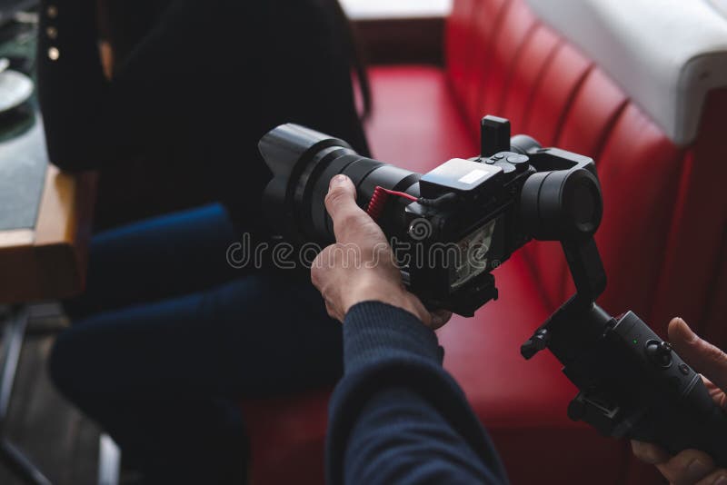 Three-axis stabilizer with camera. The operator is in the process of shooting. Equipment. The work of a videographer. Cafe stock photo