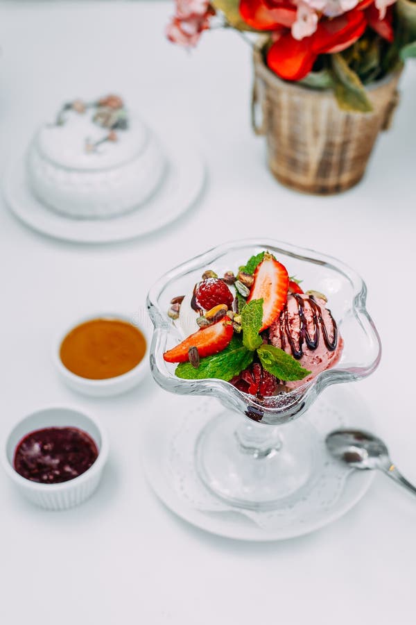 Three Balls of Ice Cream with Syrup and Fruit on a White Background
