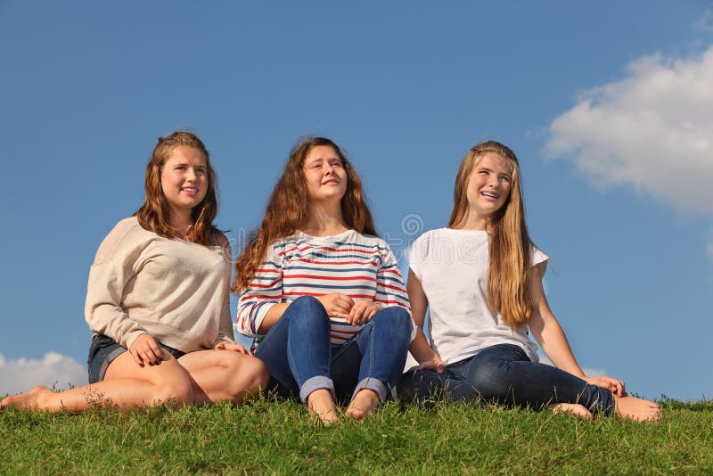 Three barefoot girls sit and look into distance