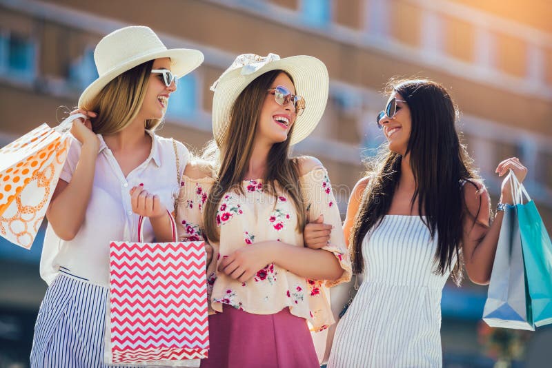 Beautiful girls in sunglasses with shopping bags in city