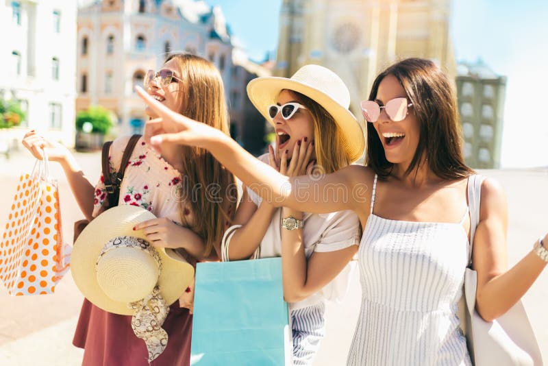 Beautiful girls in sunglasses with shopping bags in city